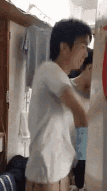 a man in a white shirt is standing in front of a mirror and looking at himself .