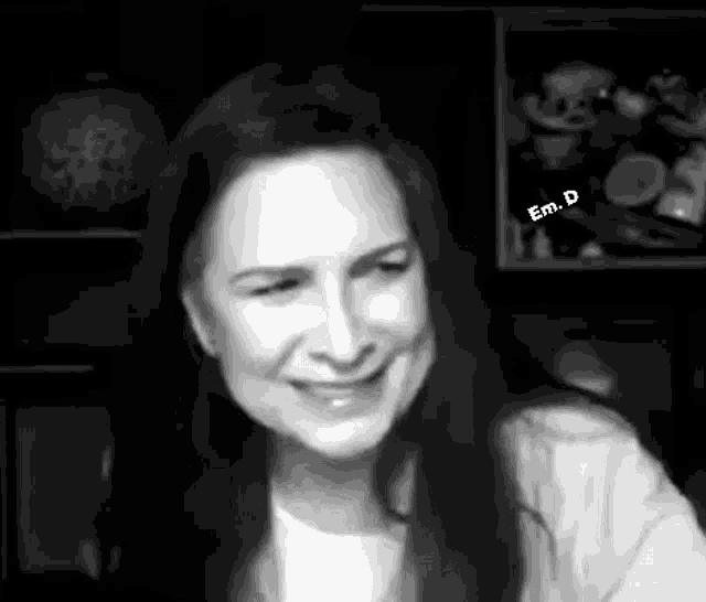 a black and white photo of a woman with long hair smiling .