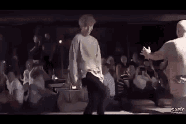a group of people are dancing on a stage in front of a crowd .