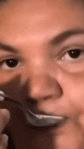 a close up of a person eating with a spoon .