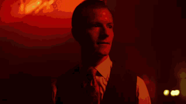 a man in a suit and tie stands in a dark room