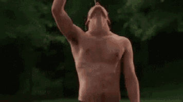 a shirtless man is drinking water from a bottle while standing in the water .