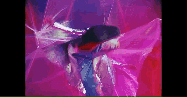 a woman is dancing in a pink plastic bag in a video .