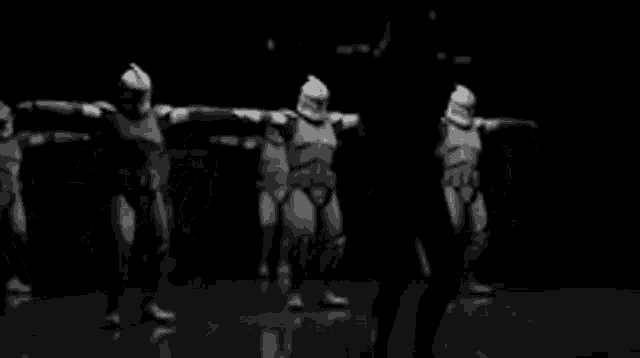 a group of stormtroopers are dancing together in a black and white photo .