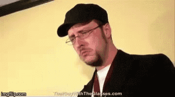 a man wearing glasses , a hat and a suit is standing in front of a wall .