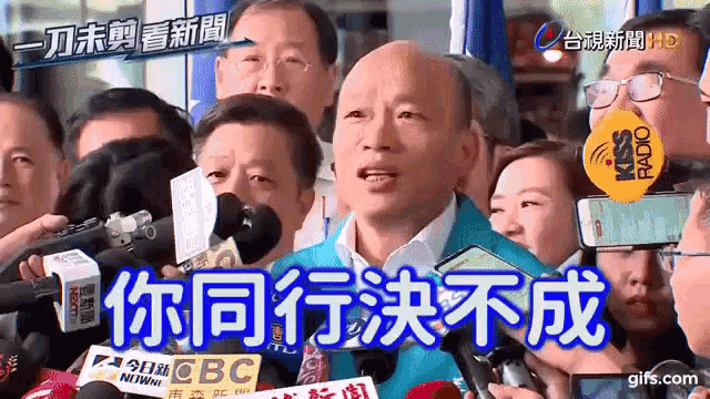 a man speaking into a microphone in front of a crowd with chinese writing on the screen