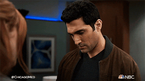a man in a brown jacket is looking at a woman in a nbc ad