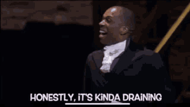 a man in a suit is laughing and saying honestly it 's kinda draining .