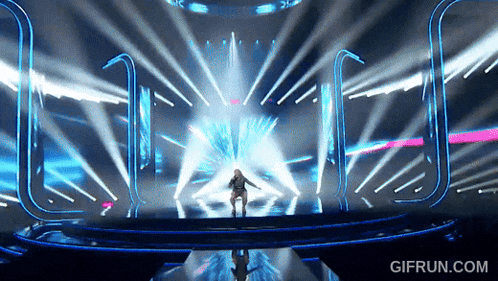 a woman singing on a stage with a gifrun.com watermark on the bottom