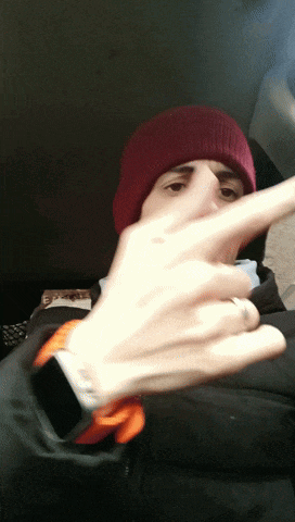 a man wearing a red beanie and a black jacket is making a peace sign