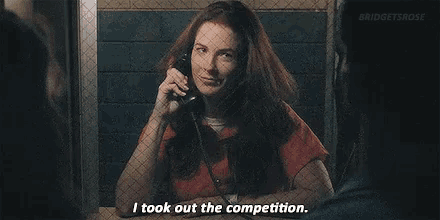 a woman in a jail cell talking on a cell phone and saying i took out the competition .
