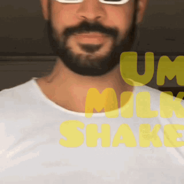 a man with a beard wearing sunglasses and a white shirt that says um milkshake