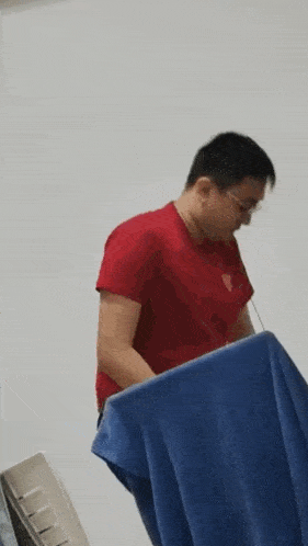a man is sitting on a bed with a blue towel on his back .