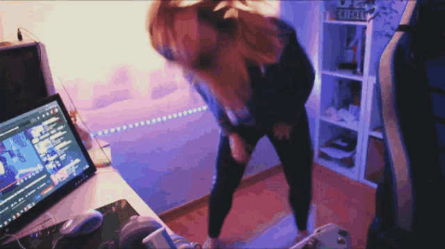 a woman is dancing in front of a computer with the word everest on the shelf behind her