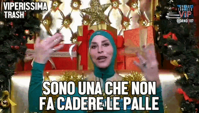 a woman wearing a hijab says sono una che non fa cadere le palle in front of a christmas tree