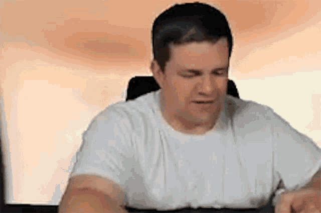 a man in a white shirt is sitting in front of a computer screen .