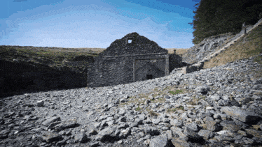a stone building sits on a rocky hillside