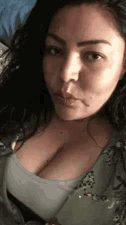 a woman with large breasts is taking a selfie with her phone .