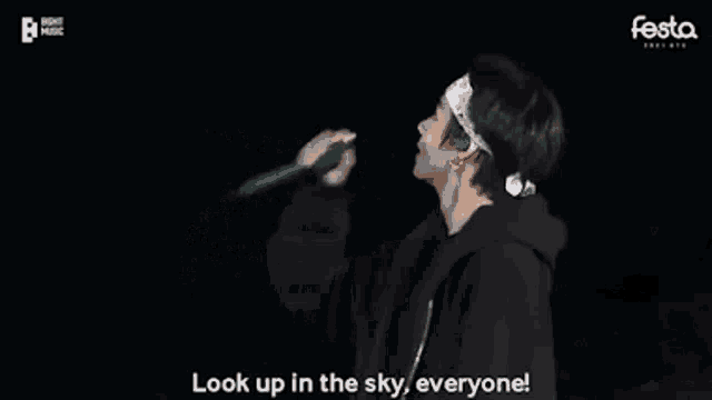a man with a bandana on his head is standing on a stage and talking to the crowd .