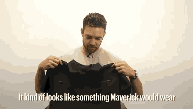 a man is holding up a black shirt that says it kind of looks like something maverick would wear