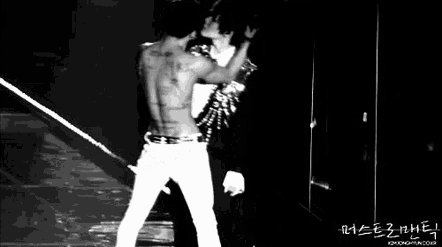 a man without a shirt is kissing another man on the stage .