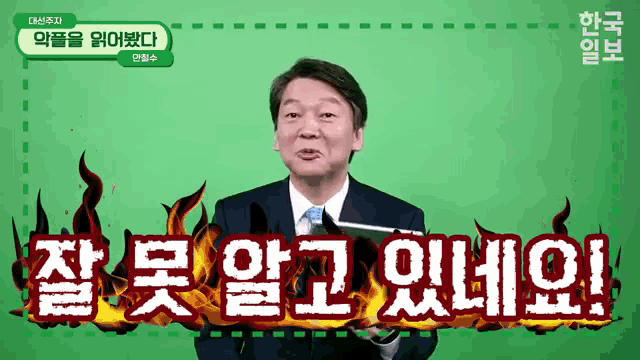 a man in a suit and tie is standing in front of a green screen with korean writing on it .