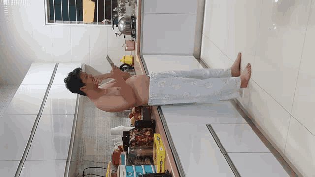 a shirtless man is laying on a kitchen counter looking at a cell phone