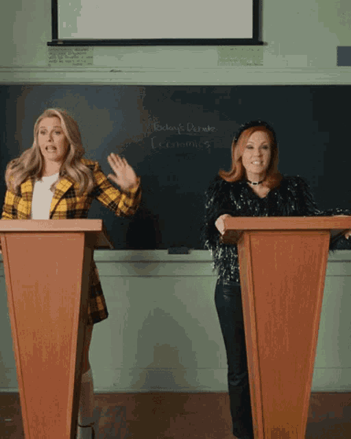 two women giving a speech in front of a blackboard that says today 's debate economics