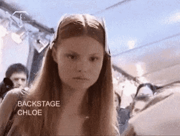 a woman with long red hair is standing in a room with the words backstage chloe written on the bottom .