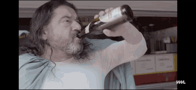 a man with long hair and a beard drinks from a bottle with the letter w on the bottom