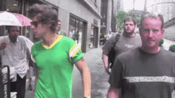 a man in a green shirt is walking down the street with other men