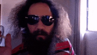a man with a beard is wearing sunglasses and holding a toothbrush