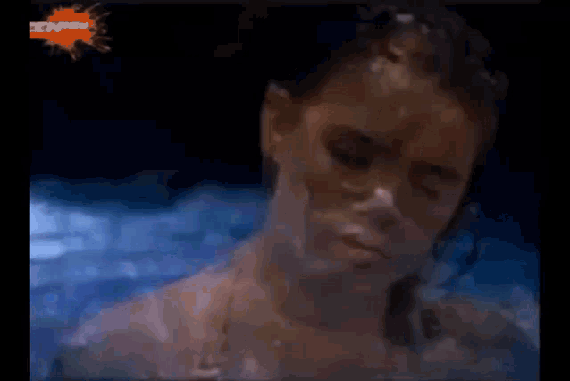 a woman is laying in the water with her eyes closed and a nickelodeon logo in the background .