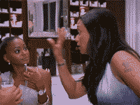 two women are standing in front of a mirror and one is applying makeup to the other 's face