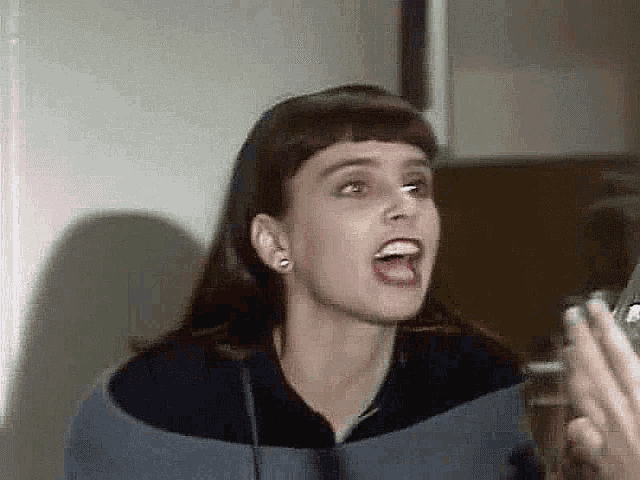a woman is making a funny face with her mouth open while holding a glass .