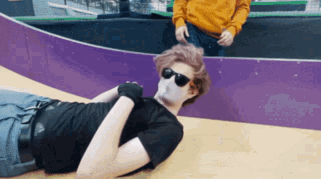 a man wearing sunglasses and gloves laying on the ground