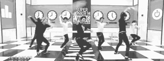 a black and white photo of a group of people dancing on a checkered floor .