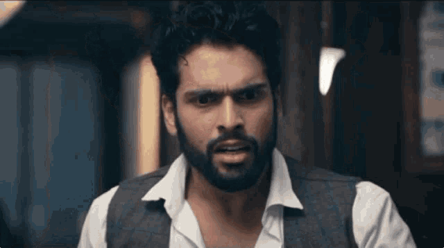a man with a beard wearing a vest and white shirt