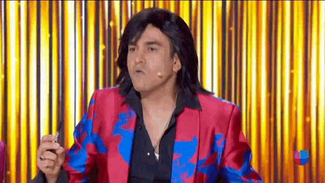 a man in a red and blue jacket is smoking a cigarette while wearing a wig .