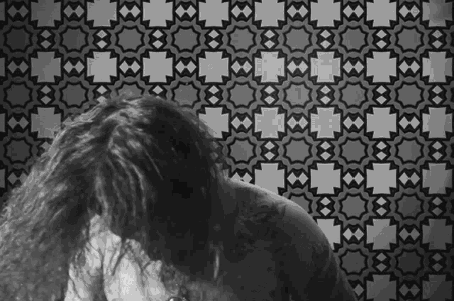 a black and white photo of a man with tattoos on his chest