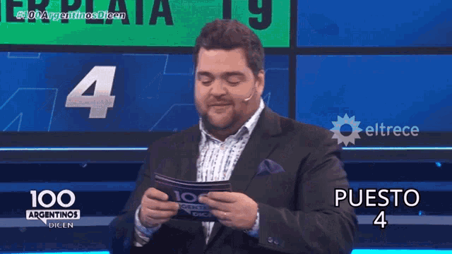 a man in a suit stands in front of a screen that says 100 argentinas