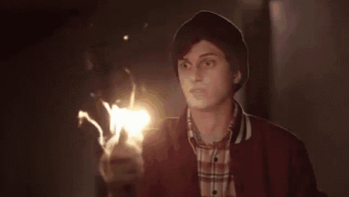 a young man in a red jacket and plaid shirt is holding a torch .