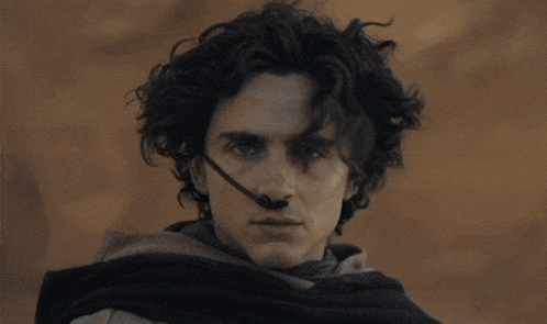 a man with curly hair and blue eyes wears a black nose clip