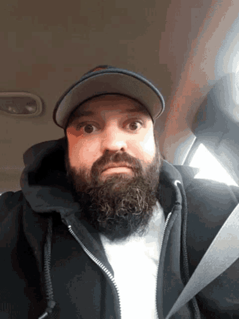 a man with a beard wearing a hat and jacket