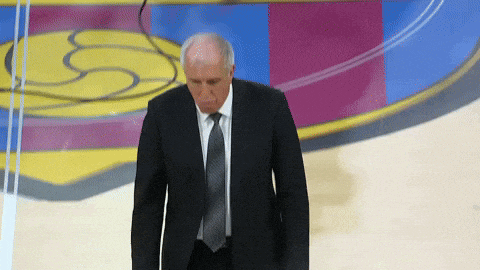 a man in a suit stands in front of a basketball court