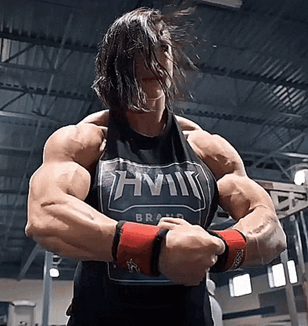 a woman is flexing her muscles in a gym wearing a tank top that says anvil