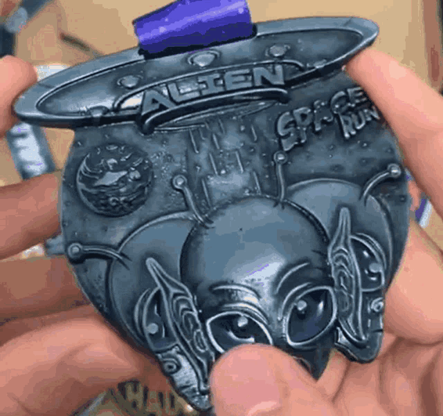 a person is holding a medal that says alien space run on it