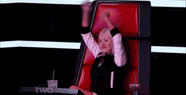 a woman is sitting in a chair with her arms in the air