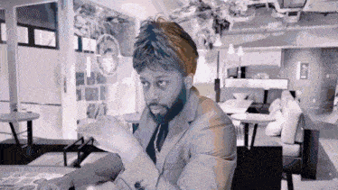 a man with a beard is sitting at a table in a room