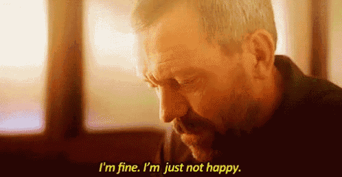 a man is sitting in front of a window and saying `` i 'm fine , i 'm just not happy  ''